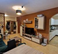 Living room in a three-room apartment with a wooden decor floor and an open kitchen.