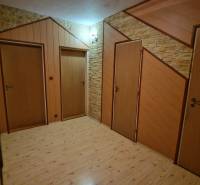 A hallway with three doors and a floor with a wooden decor in a 3-room apartment.