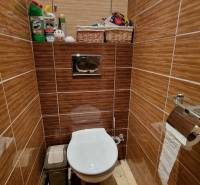 A toilet with brown tiles, a white bowl, and storage baskets in a 3-room apartment.