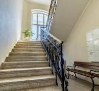 A staircase with a metal railing and a bench in the offices, illuminated by a large arched window.