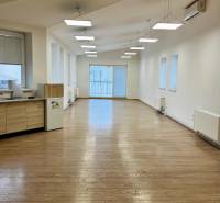 Offices with wood-patterned flooring and large windows, suitable for business.
