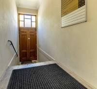 A narrow staircase with a ladder and a lamp leads to a wooden door. Offices.