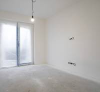An empty room in a family house with a hanging light bulb and closed doors to the terrace.