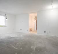Interior of a family house under construction with a concrete floor, white walls, and electrical installation preparation.