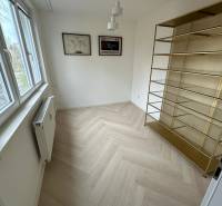 A room in a 2-room apartment with a shelf, a wooden decor floor, and a window.