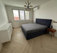 Bedroom with a bed, white dresser, wood-patterned floor, and pendant light.