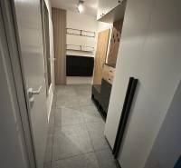 Hallway in a 2-room apartment with tiles, cabinets, and wooden wall panels.