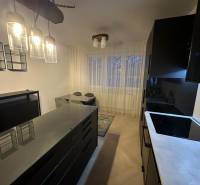 A kitchen in a 2-room apartment with glass light fixtures and a wooden decor floor.