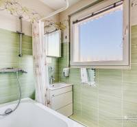 A bathroom in a 4-room apartment with a bathtub, green tiles, and a mirror.