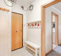 Entrance hallway in a 4-room apartment, white walls, coat hooks, and a bench.