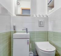 A bathroom in a 4-room apartment with a toilet and a sink, with tiled walls.