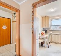 Interior of a 4-room apartment with a wooden decor floor and a light kitchen.