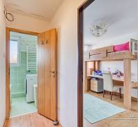A hallway with a bathroom and a children's room in a 4-room apartment, flooring with a wooden decor.