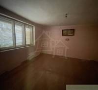 An empty room in a family house with wood-patterned flooring and a large window.