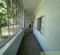 A narrow glass-enclosed space in a family house with a view of the garden.