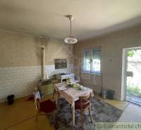 A kitchen in a family house with a table, tiles, and access to the garden.