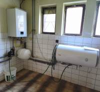 Boiler room in a family house with a gas boiler and a water heater, white tiles on the walls.
