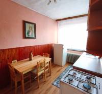 A kitchen in a family house with a wooden table, a gas stove, and a floor with a wooden decor.