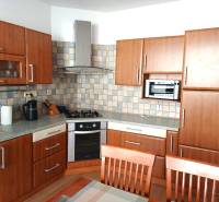 A kitchen in a 3-room apartment with a wood-patterned floor and kitchen cabinets.