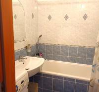 Bathroom in a 3-room apartment with a bathtub, sink, and washing machine. Blue tiles.