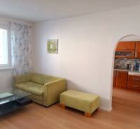 Living room in a 3-room apartment with a sofa, table, and kitchenette.