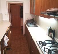A kitchen in a 2-room apartment with a gas stove and wooden decor cabinets.