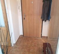 Entrance hall of a 2-room apartment with ceramic flooring and jackets on a coat rack.