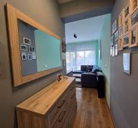 A hall in a holiday apartment with a wood-patterned floor and a mirror on the wall.