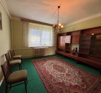 Living room with carpet and furniture in a family house, softly lit by a chandelier.
