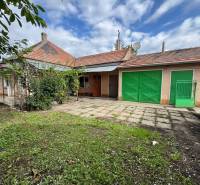 Garden and terrace at a family house in Komárno with garage doors and garden vegetation.