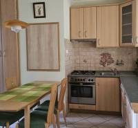 A kitchen in a 3-room apartment with a wooden decor and a dining table with four chairs.