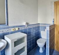 A bathroom with gray-blue tiles, a sink, and white storage furniture in a 3-room apartment.