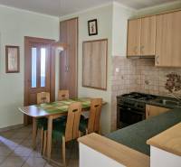 A kitchen in a 3-room apartment with a dining table and wooden cabinets.