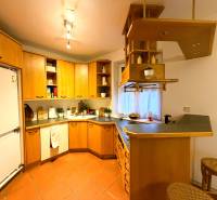 A kitchen in a 3-room apartment with wooden cabinets and a bar counter.