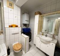 Bathroom in a 3-room apartment with a bathtub, toilet, and washing machine, white tiles.