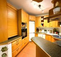 A kitchen in a 3-room apartment with a corner unit and a floor with a wood decor.