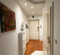 A hallway in a 3-room apartment with white furniture and a painting on the wall.