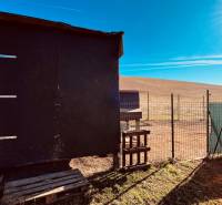 A wooden shelter and fencing on a field in the Construction of houses in Prosačov.