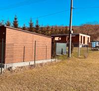 Construction of houses in Prosačov, Prosačov: fence, wooden structure, trees, and blue sky.