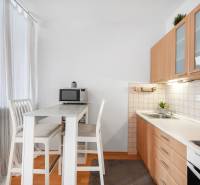 Kitchen in a studio apartment with a bar table, chairs, and a kitchen unit.