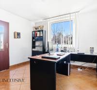 An office with a computer, a shelf, and a window with vertical blinds in commercial premises.