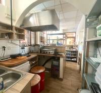 Gastro premises with wooden decor, kitchen unit, extractor hood, appliances, shelves, chairs.