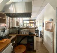 A kitchen space with a stainless steel range hood and a wooden decor floor in a gastro area.