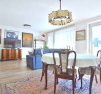 Living room with a dining table, sofa, and wood-patterned flooring in a 3-room apartment.