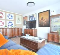 Living room in a 3-room apartment with wooden furniture, a floor with a wooden decor, and paintings on the walls.