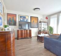 Living room with dark furniture, wood-patterned flooring, and decorative paintings in a three-room apartment.