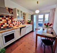 A kitchen in a 4-room apartment with colorful tiles, a counter, and a table with flowers.