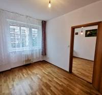 A room with a wooden decor floor in a 4-room apartment, light curtains on the window.