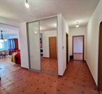 A hallway with tiles, a built-in wardrobe, and an entrance to the living room in a 4-room apartment.