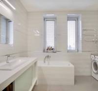 A bathroom in a 3-room apartment with a shower, a washing machine, and windows with blinds.